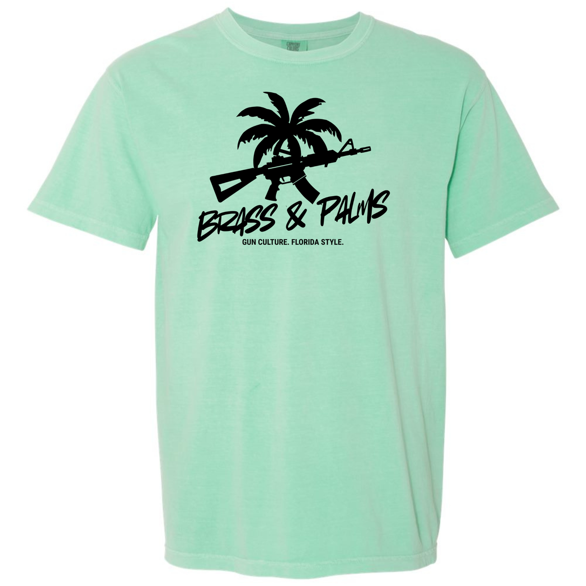 An Island Reef green short-sleeve t-shirt with a black graphic on the chest featuring a palm tree, rifle silhouette, and the text 'BRASS & PALMS' and 'Gun Culture. Florida Style.