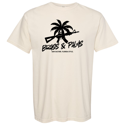 An off-white Ivory crewneck t-shirt featuring a black graphic print of a palm tree, a rifle, and the text 'BRASS & PALMS' with 'GUN CULTURE, FLORIDA STYLE.' underneath.