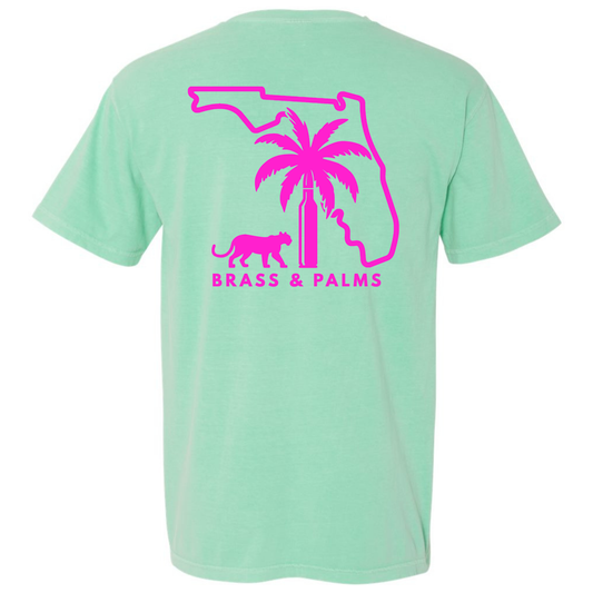 An Island Reef green short-sleeve t-shirt with a bright pink graphic on the back. The graphic features the outline of Florida, a palm tree, a panther, and the text 'BRASS & PALMS'.