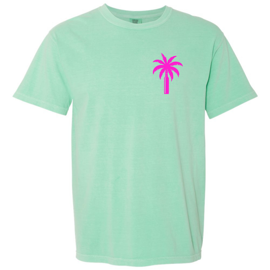 An Island Reef green short-sleeve crewneck t-shirt featuring a small bright pink palm tree graphic on the left chest, displayed against a solid white background.
